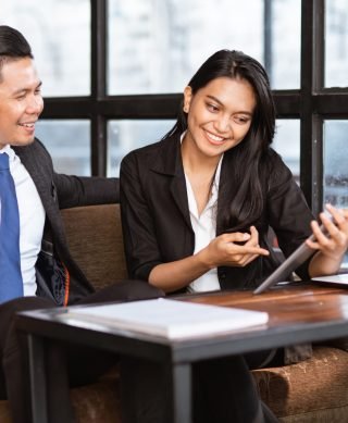 businessman and woman having a relaxed meeting using tablet in cafe happy asian businessman and woman having a relaxed meeting using tablet in cafe